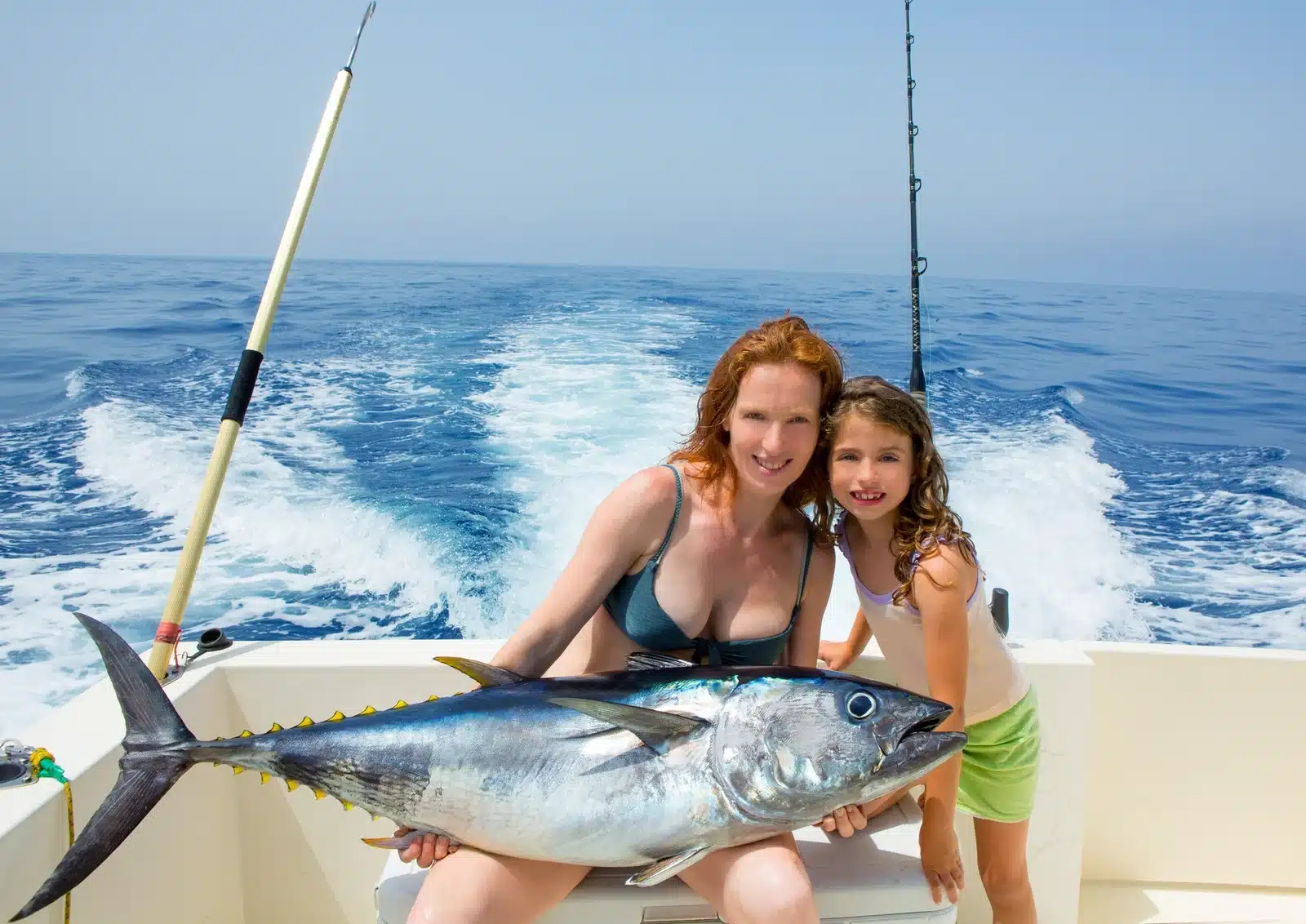Bikini fisher woman and daughter girl holding big bluefin tuna catch on boat deck 1767007840501