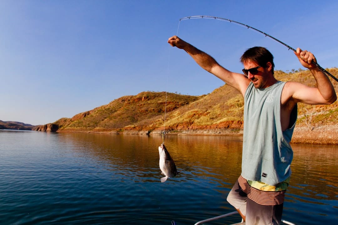 Angler on an offshore boat engaged in a strenuous battle with a large fish, their fishing rod bent dramatically under the ...