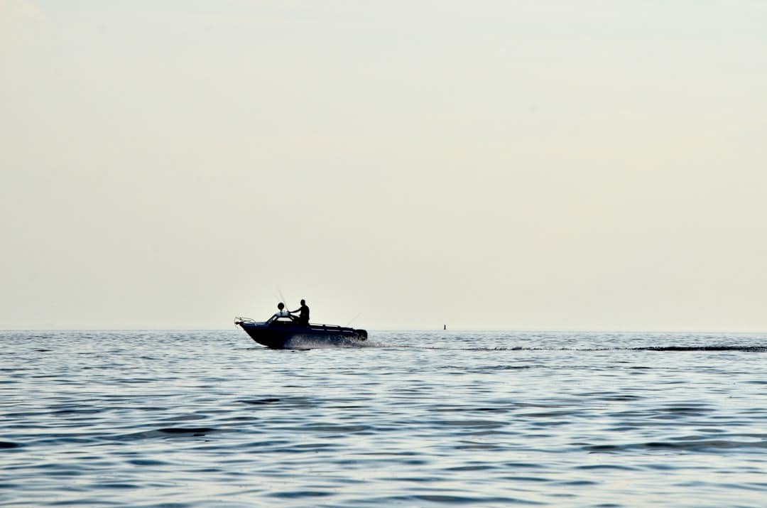 Action shot of a fisherman on a boat, straining to reel in a large fish with the fishing rod bent under pressure.
