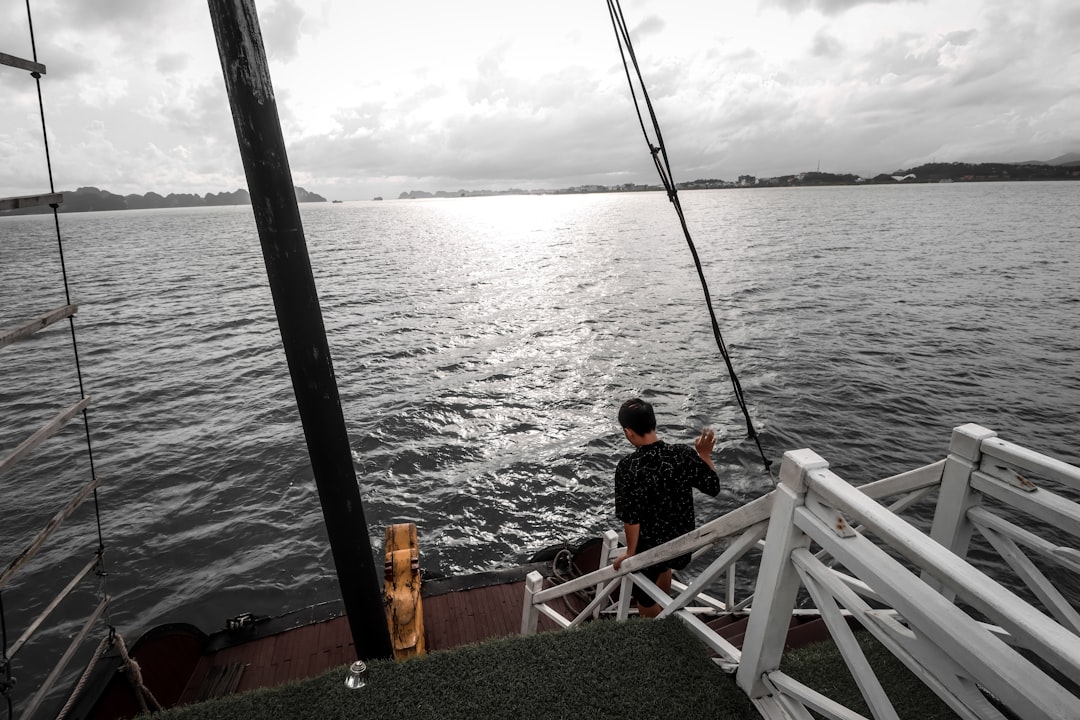 A professional angler stands on a boat, intently focused on the calm ocean ahead, embodying the expertise needed to find fish on a quiet day.